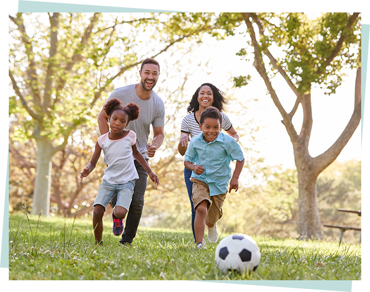 Image showing a young family playing football in an outdoor setting.